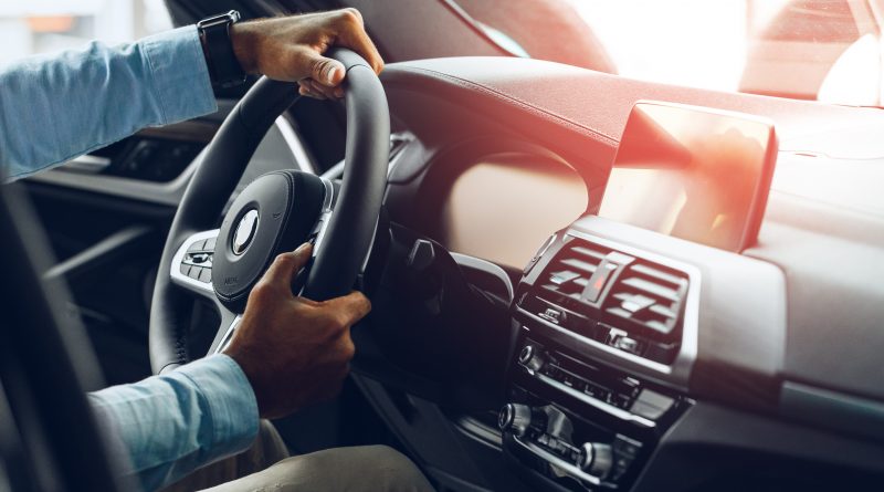 Muž držiaci volant luxusného automobilu značky BMW.